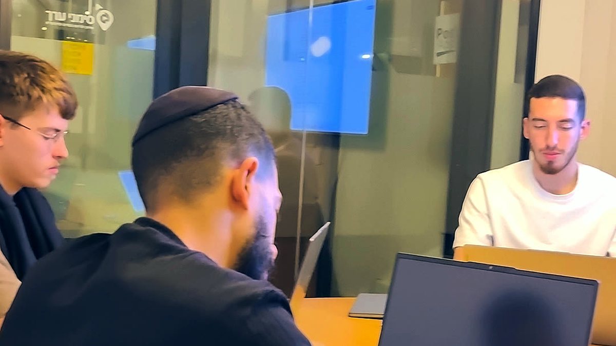 שלושה סוחרים יושבים סביב שולחן עם מחשבים ניידים במפגש ליווי